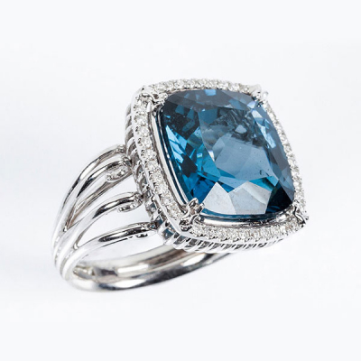 Sortija en montura calada de oro blanco 18 K, con un topacio azul &#039;London&#039; cuadrangular, en garras, y orla en fila de limpios y blancos diamantes talla brillante