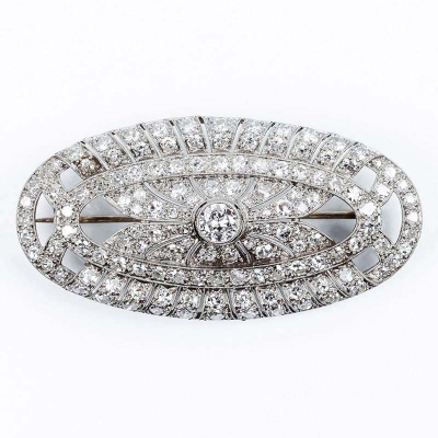 Bello broche antiguo &#039;art-decó&#039; en montura oval de oro blanco, con un blanco diamante central, talla brillante