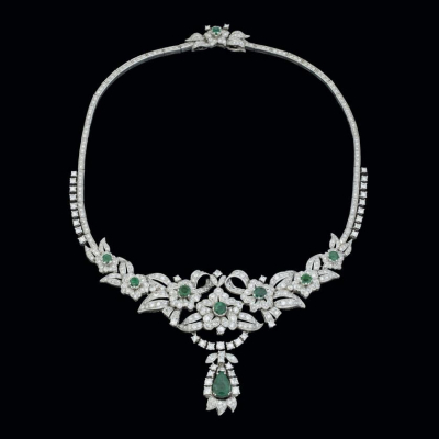 Collar de oro blanco de 18 K. con una esmeralda talla pera y siete talla redonda sobre secciones en forma de flor y cintas curvas cuajadas de diamantes.