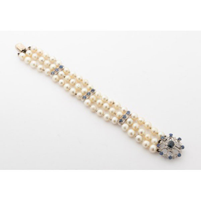 Pulsera en oro blanco con 3 filas de perlas cultivadas y 3 barras con 9 zafiros azules, cierre en forma de flor con zafiro central