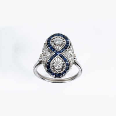 Delicada sortija lanzadera estilo art-decó en platino, con diamantes, talla brillante, y  zafiros finos azules calibrados 