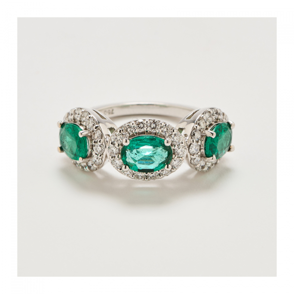 Sortija en oro blanco con tres rosetones de esmeraldas colombianas talla oval orladas por dikamantes talla brillante.