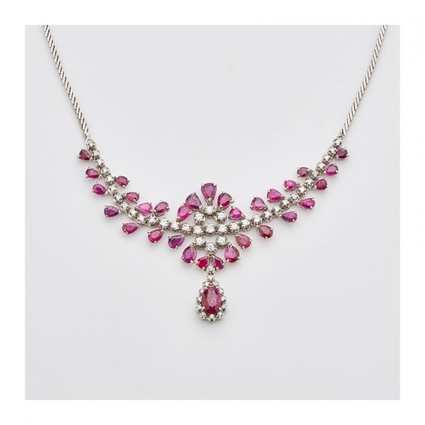 Gargantilla en oro blanco con tira central de diamantes talla brillante custodiada por rubíes tallas perilla y trillón y rematados por lágrima de rubí talla oval orlado por brillantes.