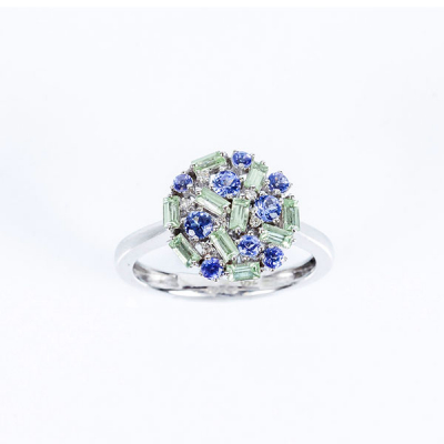 Sortija en oro blanco 18 K, con motivo circular cuajado de piedras finas, (amatistas verdes y tanzanitas), salteadas con diamantitos 
