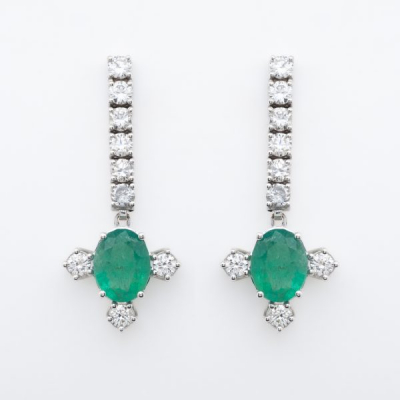 Pendientes largos en oro blanco con tira de diamantes talla brillante rematada por esmeralda talla oval flanqueada por tres diamantes.