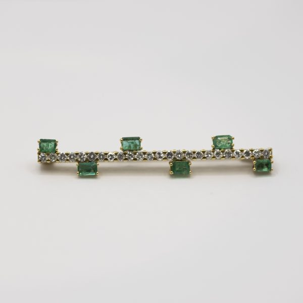 Aguja lanzadera en oro con esmeraldas rectangulares engastadas en garras y diamantes talla brillante, 6,5 cm.