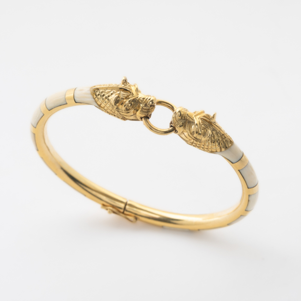 Pulsera esclava en oro y aplicaciones de hueso a tramos alternados con decoración central de dos cabezas de felino enfrentadas.