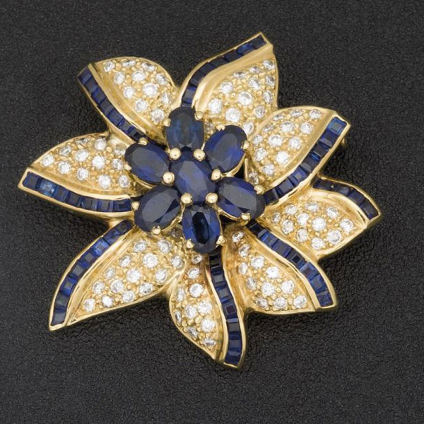 Broche de oro amarillo de 18 K. realizado en forma de flor con zafiros azules talla oval  y calibrados y pavé de brillantes.
