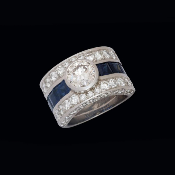 Anillo de oro blanco de 18 K. con brillante central de 1,49 cts. engastado en chatón, zafiros azules y brillantes