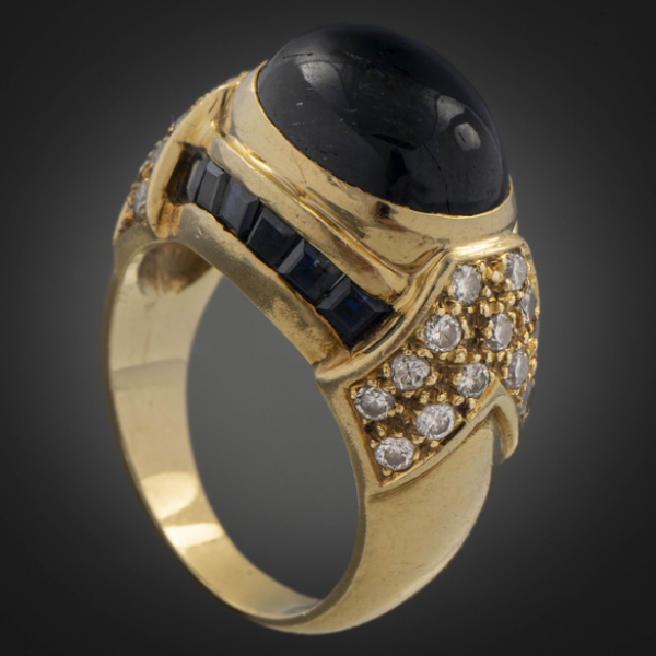 Anillo en oro amarillo de 18 kt con zafiro en talla cabujón con brillantes y zafiros calibrados.