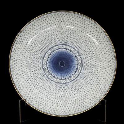Plato de porcelana con decoraciones en azul bajo vidriado y borde dorado. 