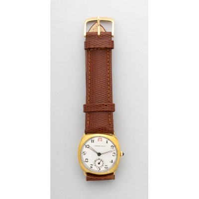Reloj marca Tiffany and Cº con caja chapada en oro, esfera blanca y números árabes. Correa en piel marrón. Cuerda.