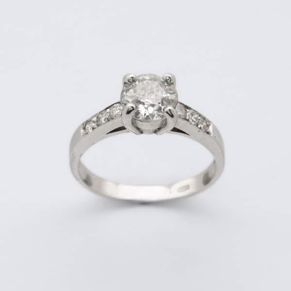 Sortija en oro blanco con diamante central talla brillante antigua y brazos de diamantes talla brillante.