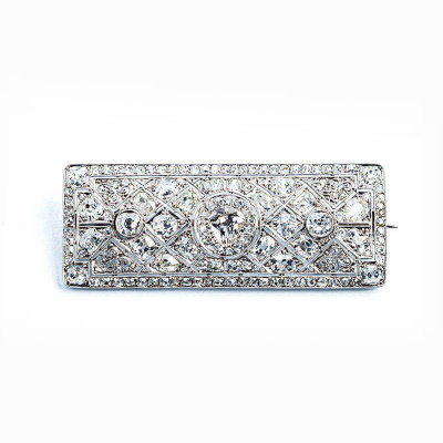 Espléndido broche antiguo, &#039;art-decó&#039;, en platino, cuajado de blancos diamantes talla brillante antigua, y talla &#039;cojín&#039;, en decoración grafilada, con un limpio y blanco diamante central, talla oval