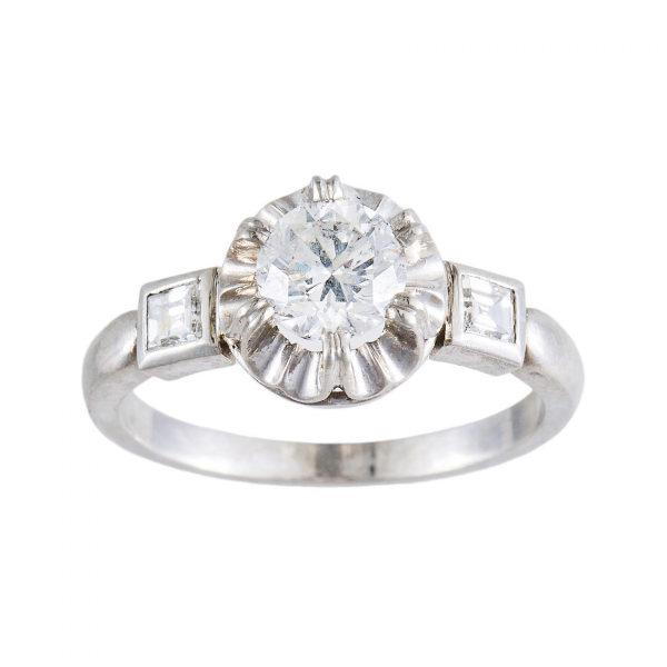 Sortija en oro blanco con diamante talla brillante engastado en garras y custodiado por diamantes talla princesa engastados en chatón.