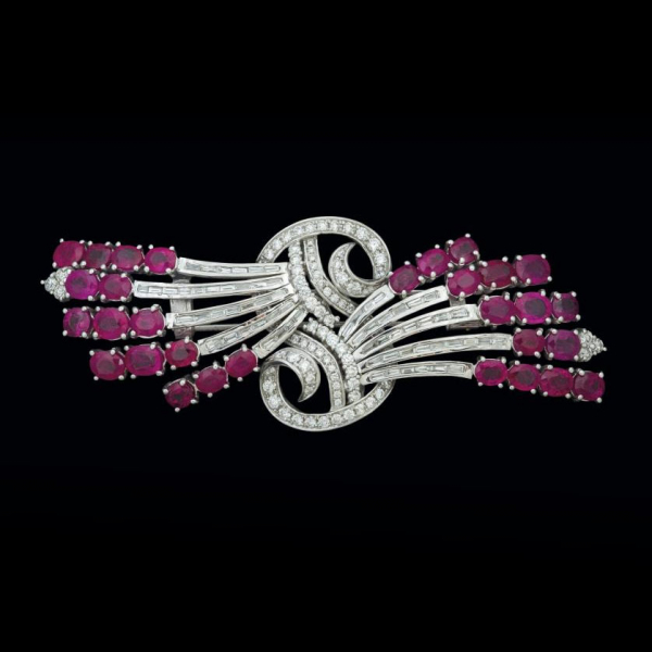Gran broche de oro blanco de 18 K. con rubíes talla oval (21,30 cts.), brillantes y diamantes alla esmeralda  