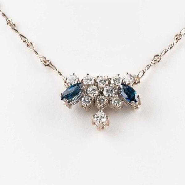 Cadenita vintage (oro blanco 18 K o platino) con centro colgante cuajado de limpios y blancos diamantes, talla brillante, en garras, y zafiros finos azules, talla marquisse.