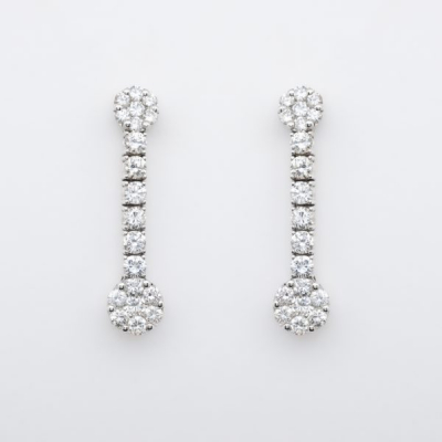 Pendientes largos en oro blanco con dos rosetones unidos por l&iacute;nea de diamantes talla brillante.
