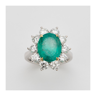 Sortija rosetón en oro blanco con esmeralda colombiana talla oval orlada por diamantes talla brillante.