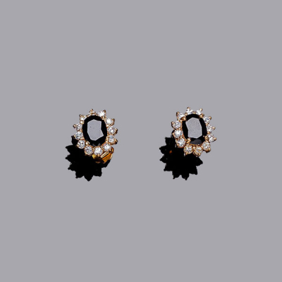 Pendientes en oro amarillo con zafiro azul, talla oval, en garras, y orla de circonitas (2 zaf.: 3.40 ct aprox.).