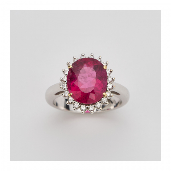 Sortija rosetón en oro blanco con turmalina rubelita talla oval orlada por diamantes talla brillante.