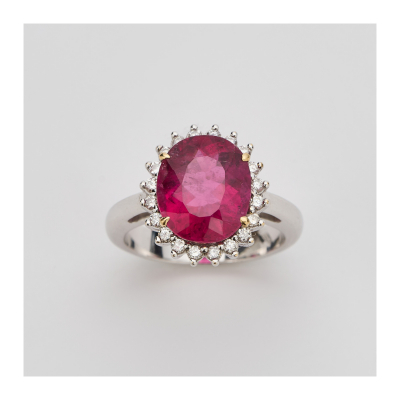 Sortija rosetón en oro blanco con turmalina rubelita talla oval orlada por diamantes talla brillante.