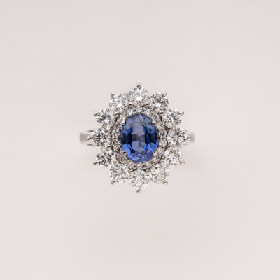 Sortija roset&oacute;n en oro blanco con zafiro azul de Ceil&aacute;n talla oval y doble orla de diamantes talla brillante.