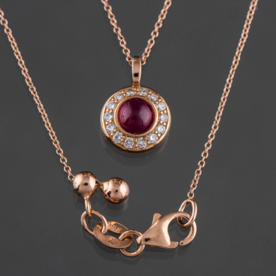 Bonita cadena en oro rosa de 18kt con colgante en forma de rosetón con rubí en cabujón y orlado de brillantes.
