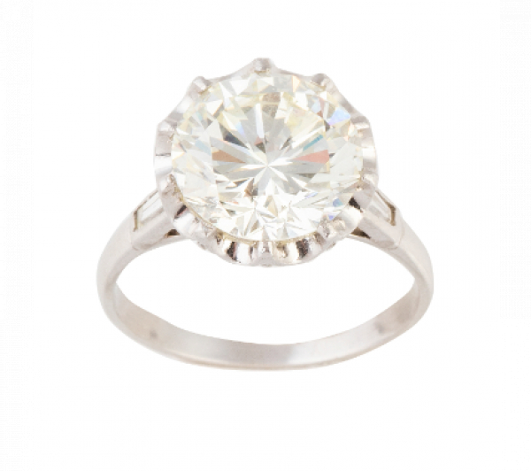 Sortija con solitario central de 3,43 ct entre dos baguettes de diamante que rematan los brazos de la montura.   En oro blanco de 18 K.