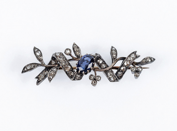 Alfiler antiguo en montura de oro rosa, diseño de ramita y lazo cuajados de limpios y blancos diamantes sobre vistas de plata