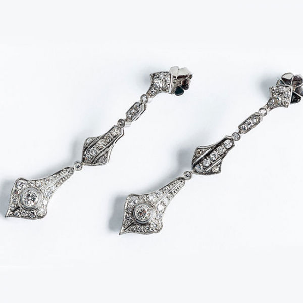 Delicados pendientes largos, estilo art-decó, en platino con un limpio y blanco diamante central, talla brillante 