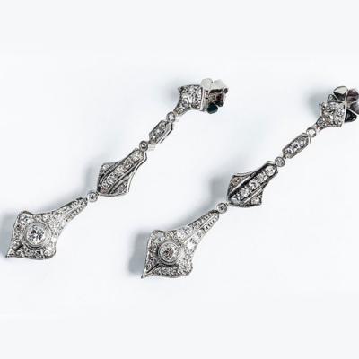 Delicados pendientes largos, estilo art-decó, en platino con un limpio y blanco diamante central, talla brillante 