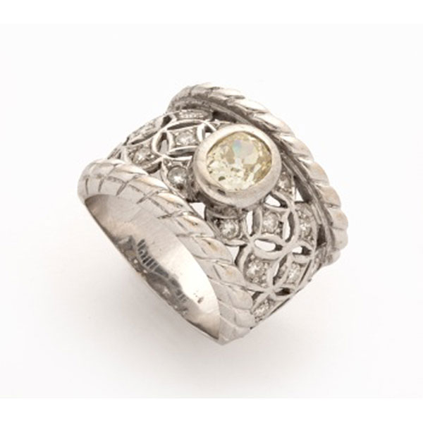 Sortija en oro blanco con diamante talla oval central, cuajados de diamantes talla brillante a los lados con decoración vegetal y cordón