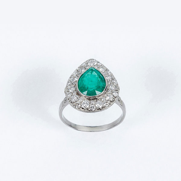 Delicada sortija en platino, con una bella esmeralda colombiana, talla perilla, y orla en pav&eacute; de limpios y blancos diamantes 
