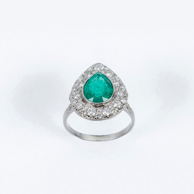 Delicada sortija en platino, con una bella esmeralda colombiana, talla perilla, y orla en pav&eacute; de limpios y blancos diamantes 