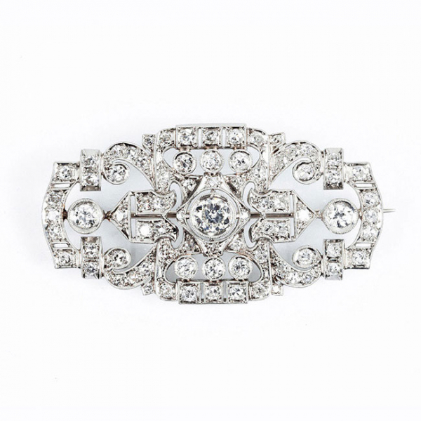 Bello alfiler antiguo, estilo 'art-decó', en sólida montura de oro blanco 18 K, en plaqueta semi-oval, con un limpio y blanco diamante central