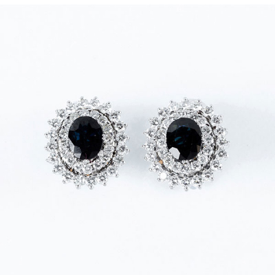 Elegantes pendientes de alta joyería, años 90, en oro blanco 18 K, con zafiro fino azul, talla oval y doble orla de limpios y blancos diamantes 