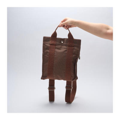 HERMÈS. Mochila modelo «Herline» en lona de tonalidad marrón con asas y correas ajustables. En perfecto estado.