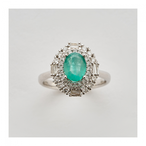 Sortija rosetón en oro blanco con esmeralda talla oval y doble orla de diamantes tallas brillante y baguette.