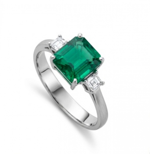 Sortija en oro blanco con esmeralda central y 2 diamantes talla princesa laterales con un peso total de 0,25 cts.