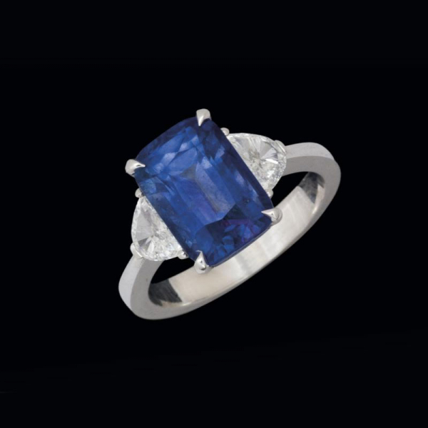 Anillo de oro blanco de 18 K. con zafiro azul talla cojín de 5,35 cts. y diamantes a los lados (0,52 cts.)