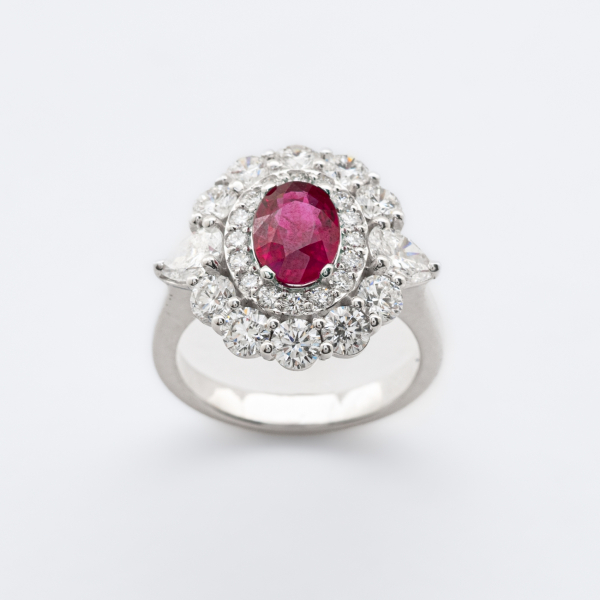 Sortija rosetón en oro blanco con rubí (Burma) talla oval y doble orla de diamantes talla brillante custodiados por diamantes talla trillón.