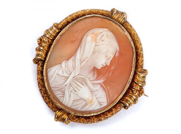 Antiguo alfiler camafeo con una bella talla neoclásica de busto de dama. Marco en volutas de oro amarillo con decoración repujada.