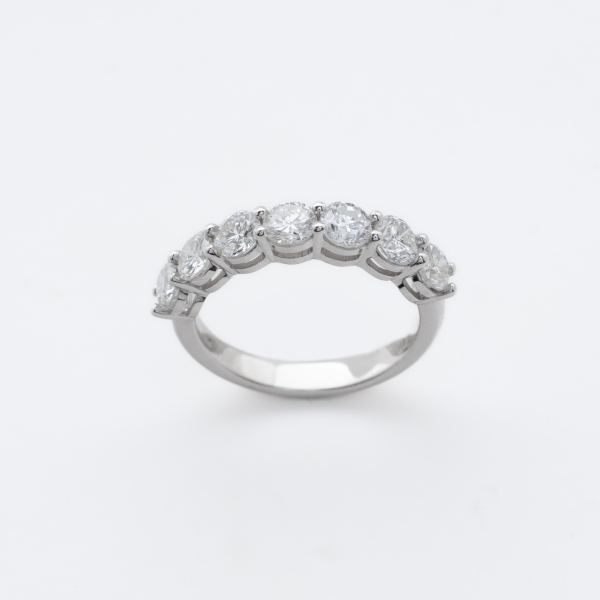 Sortija media alianza en oro blanco con diamantes talla brillante engastados en garras.