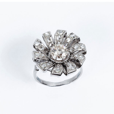 Bella sortija vintage en forma de flor, en platino, con un limpio y blanco diamante central, talla brillante orlado en &#039;pétalos&#039; cuajados de diamantitos simples en decoración grafilada
