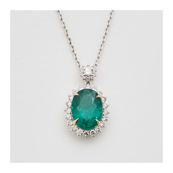 Gargantilla en oro blanco con dos rosetones de diamantes talla brillante, el principal con esmeralda central de Zambia talla oval.