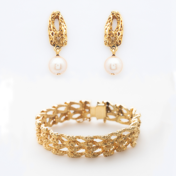 Pendientes con perla cultivada de 6,5 mm. y brazalete articulado en oro mate y brillo que presenta un patrón entrelazado y calado de acabado texturizado.