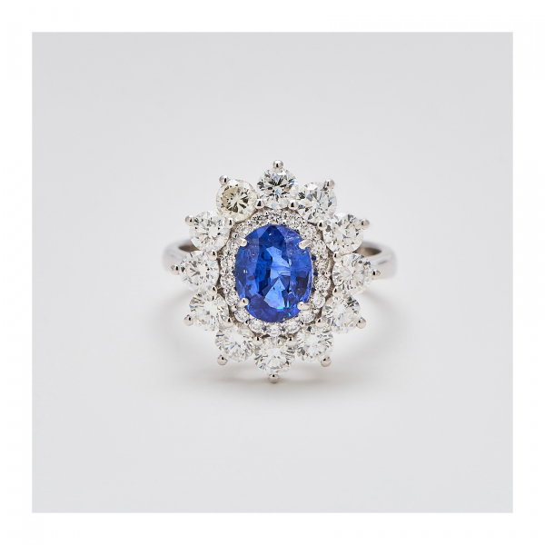 Sortija rosetón en oro blanco y zafiro azul de Sri Lanka talla oval con doble orla de diamantes talla brillante engastados en garras.