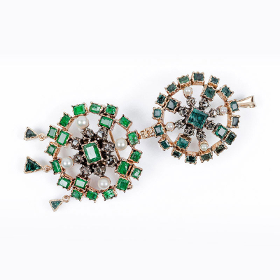 Conjunto desmontable de dos alfileres - colgantes, en rosetón calado cuajado de esmeraldas finas, con centro orlado de diamantes en vistas de plata, y perlitas