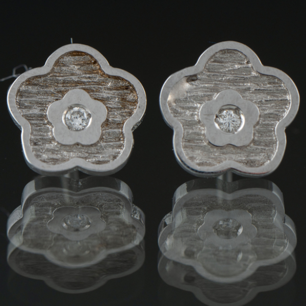 Pareja de pendientes en forma de flor en oro blanco de 18 kt con brillante central.